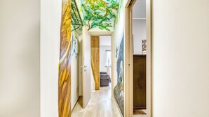 Un couloir avec un plancher en bois, une porte avec un cadre en bois et un mur orné d’une fresque.