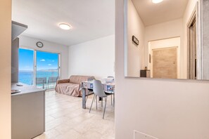 Ein modernes Wohnzimmer mit Balkon, Essbereich und Küche.