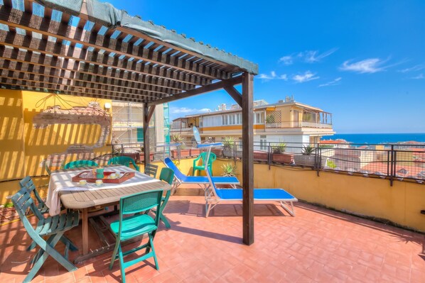 A terrace with a table and chairs, a pergola, and a view of the sea. - Ca Moretto Sea-View Terrace Apartment in Sanremo, Sanremo, Italy (Sanremo)