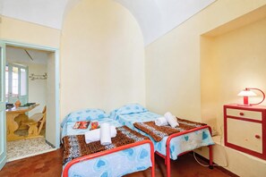 Une chambre avec deux lits, un petit bureau et une lampe rouge.