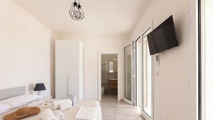 Une chambre d’hôtel moderne, équipée d’un lit, d’un téléviseur fixé au mur et d’une salle de bain visible à travers une porte ouverte.