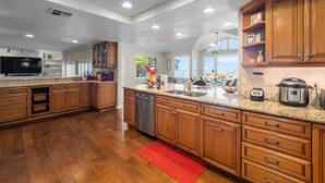 A spacious kitchen with wooden cabinets, a granite countertop, and modern appliances. - Secluded Romantic Getaway with Stunning NatureView (Anaheim)