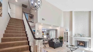 A spacious living area with a staircase, a fireplace, and a dining area. - Secluded Romantic Getaway with Stunning NatureView (Anaheim)