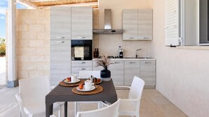 A modern kitchen with light wood cabinets, a built-in oven, and a gas stove.