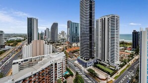 A high-rise urban area with modern buildings, a clear sky, and a view of the ocean.
