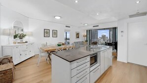 A modern kitchen with a central island, white cabinetry, and a dining area with a table and chairs.