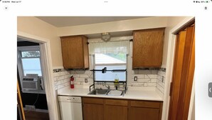 A compact kitchen with wooden cabinets, a white countertop, and a window with a view. - 3BR home 20’ Dtn Detroit, near Corewell Health Hos, Meijer’s  Major Bus Routes (Detroit)
