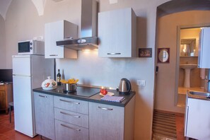 Compact kitchen with modern appliances, oven, and microwave, adjacent to a bathroom with sink and mirror.