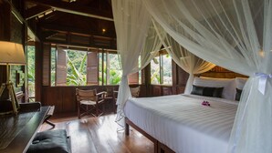 A bedroom with a canopy bed, wooden furniture, and large windows with shutters. - The Luang Say Lodge (Pakbeng)