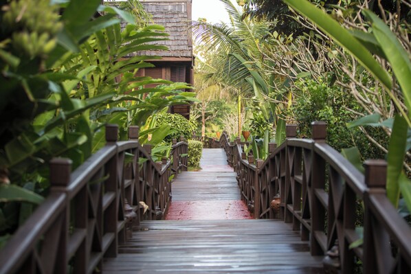 A wooden bridge with railings, surrounded by lush greenery.