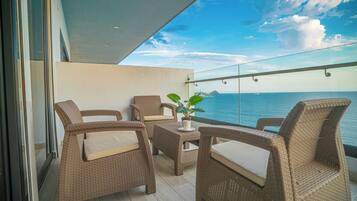Enjoy the ocean view from this balcony with wicker chairs and a small table.