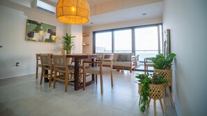 A spacious dining area with a wooden table and chairs, a hanging light fixture, and large windows offering a view. - ALOHA MAZATLAN (Mazatlán)