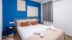 Une chambre d’hôtel équipée d’un lit, d’une table de chevet, d’un appareil de climatisation et d’une fenêtre avec des rideaux.