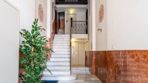 Un vaste hall d’entrée avec un sol en marbre, une plante en pot et un escalier menant à l’étage supérieur.
