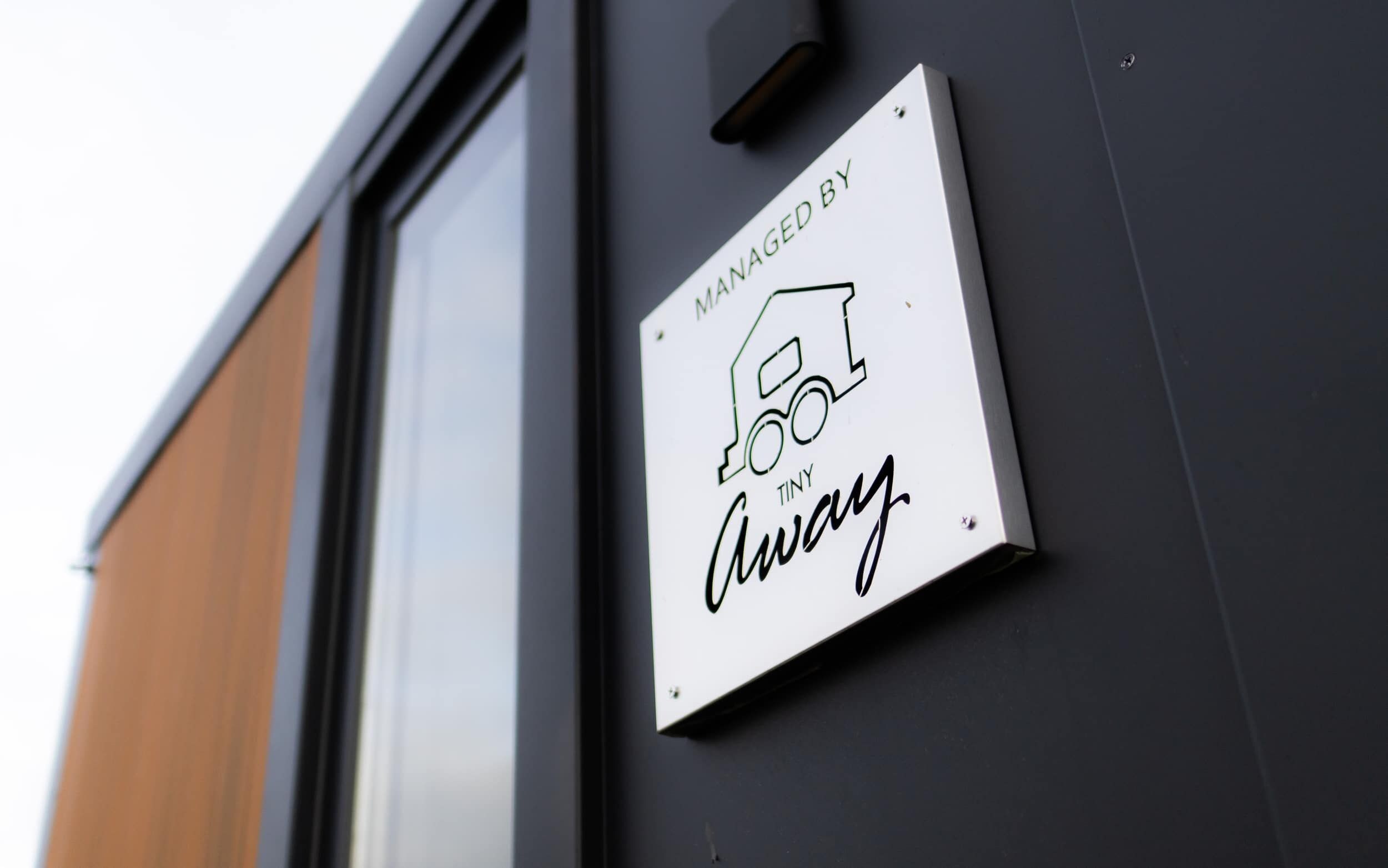 A sign on a building wall that reads "MANAGED BY TINY Away."