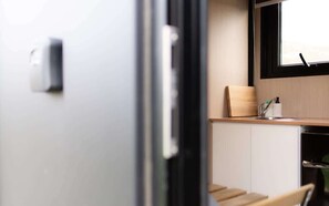 A modern kitchen with white cabinets, a wooden countertop, and a window above the sink. - Weka Pass Cottages 1 by Tiny Away (Waikari)