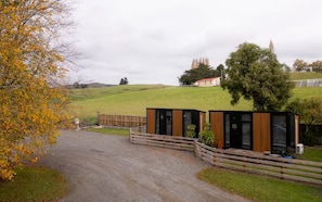 A modern building with a wooden fence and a paved driveway leading to it. - Weka Pass Cottages 1 by Tiny Away (Waikari)