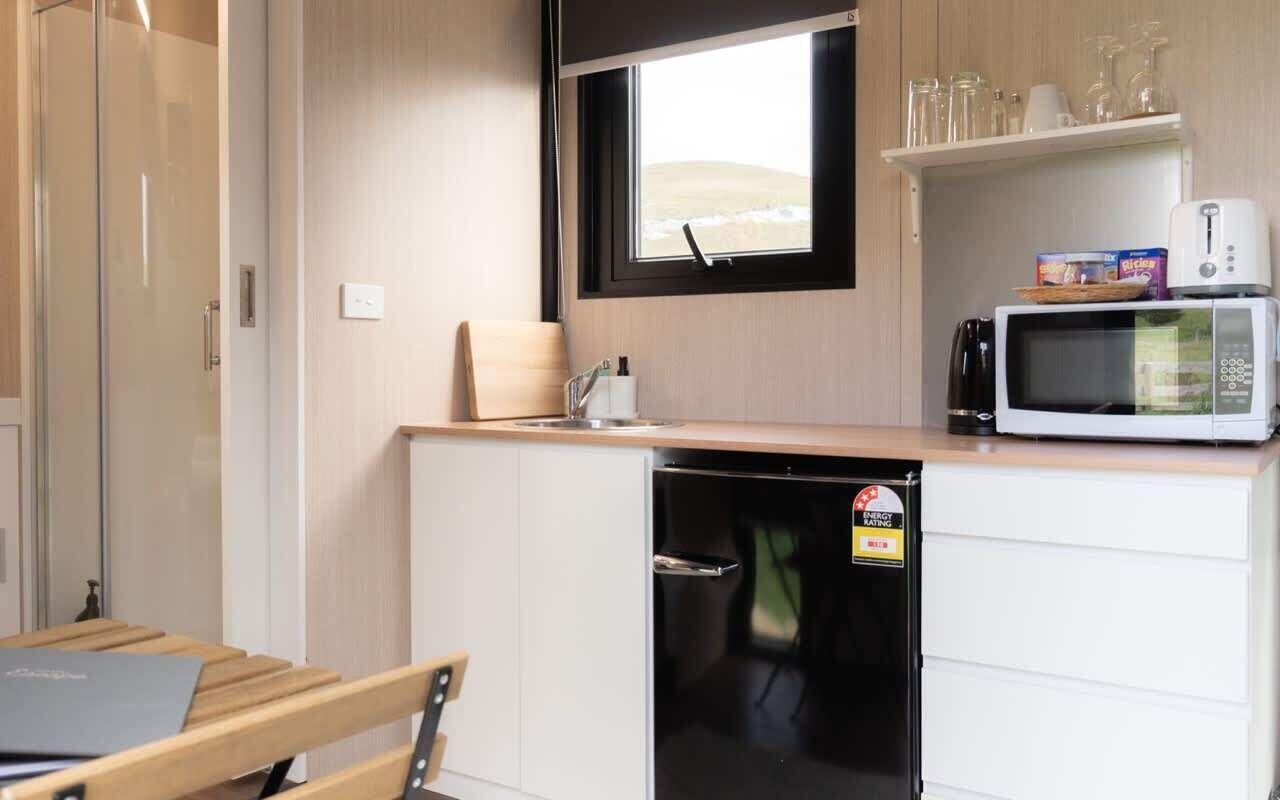 Una cocina compacta con microondas, un refrigerador pequeño y una ventana con vistas al exterior.