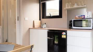 Una cocina compacta con microondas, un refrigerador pequeño y una ventana con vistas al exterior.