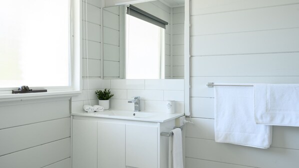 A bathroom with white tiled walls, a white sink, and a towel rack.