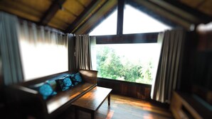 A room with a wooden bench and a view of greenery outside.
