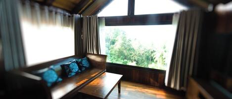 A room with a wooden bench and a view of greenery outside.