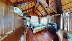 A wooden room with a bed, a desk, and a refrigerator.