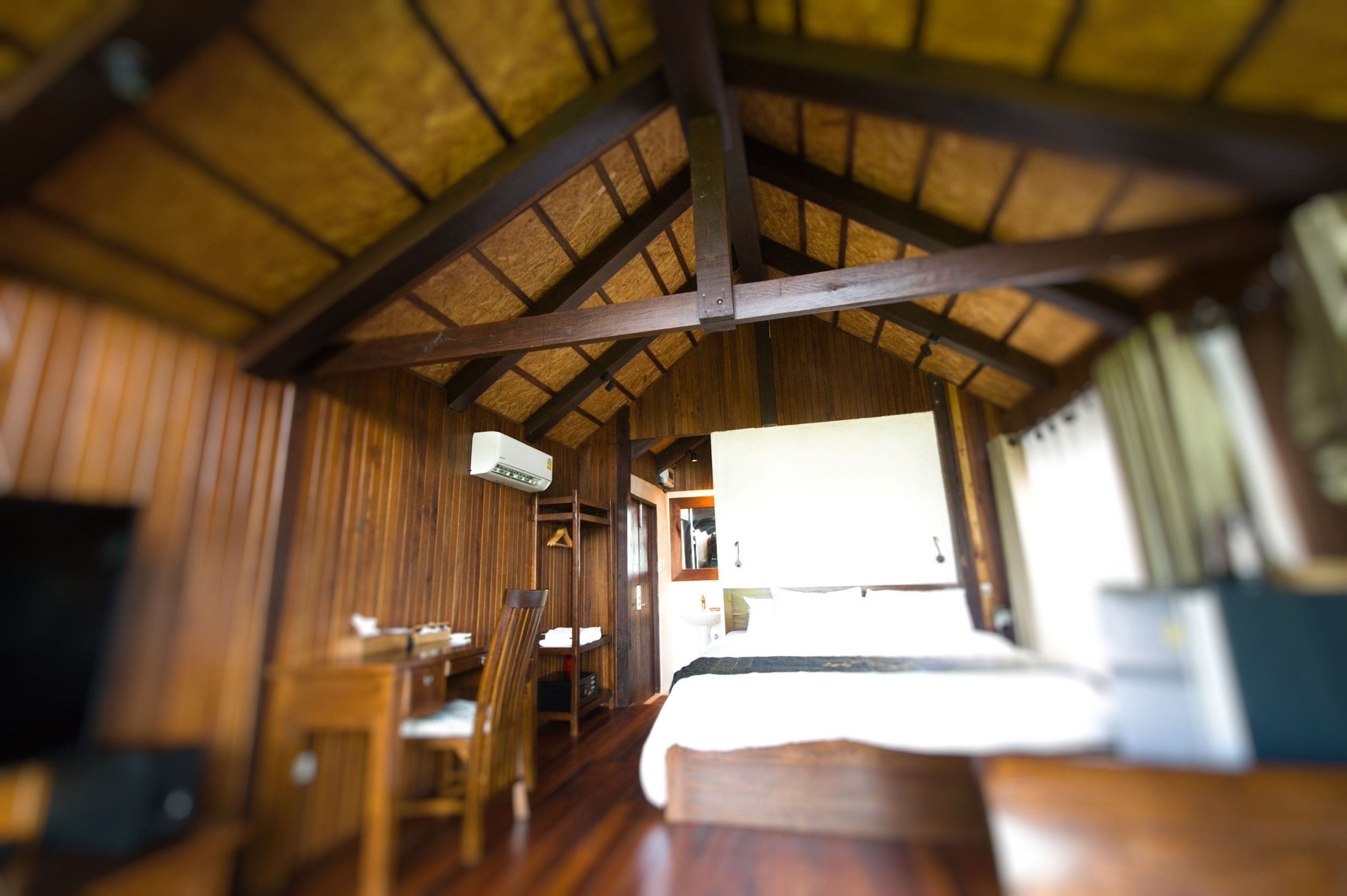 Un interior rústico con vigas de madera, una cama, una silla y una pequeña mesa.