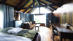A room with a bed, a sofa, a small table, and a window with curtains.