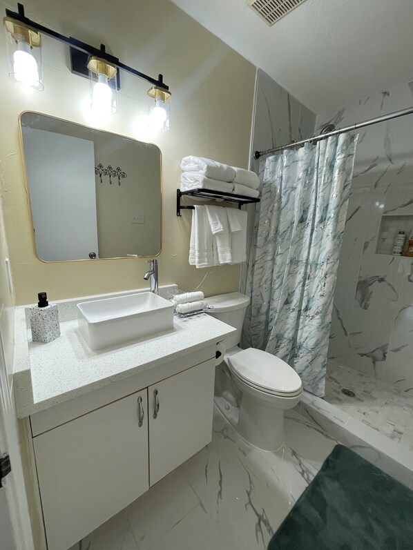 A modern bathroom with a white sink, mirror, and toilet. There is a towel rack with folded towels and a shower curtain. - Charming 3-bedroom house in peaceful Arlington with WiFi, AC (Arlington)
