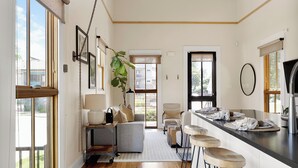 A modern kitchen with a bar area, a sofa, and a dining table.