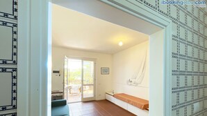Una habitación con un amplio ventanal corredera que da a un patio, una banca y una pared con una pintura de un velero.