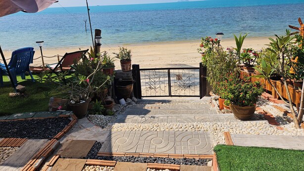 A patio with a view of the sea, outdoor furniture, and potted plants.