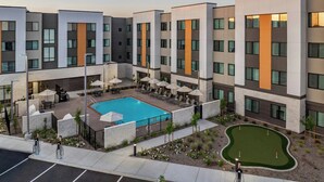 A modern hotel with a swimming pool, outdoor seating, and a golf putting area. - Residence Inn by Marriott Sacramento Cal Expo (Sacramento)