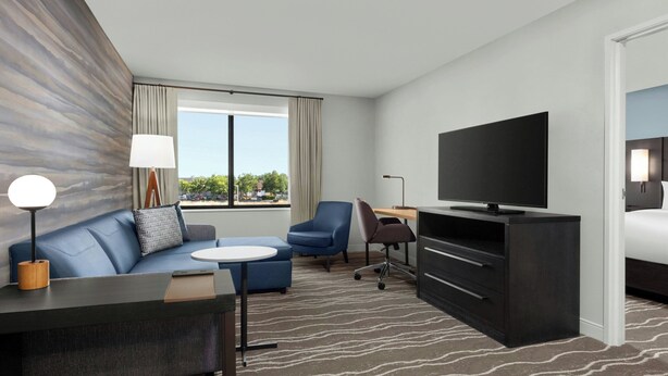 Een moderne hotelkamer met een bank, een klein tafeltje, een televisie, een bureau en een bed.