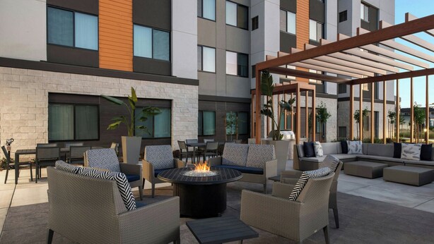 An outdoor patio with wicker furniture, a central fire pit, and a pergola. - Residence Inn by Marriott Sacramento Cal Expo (Sacramento)