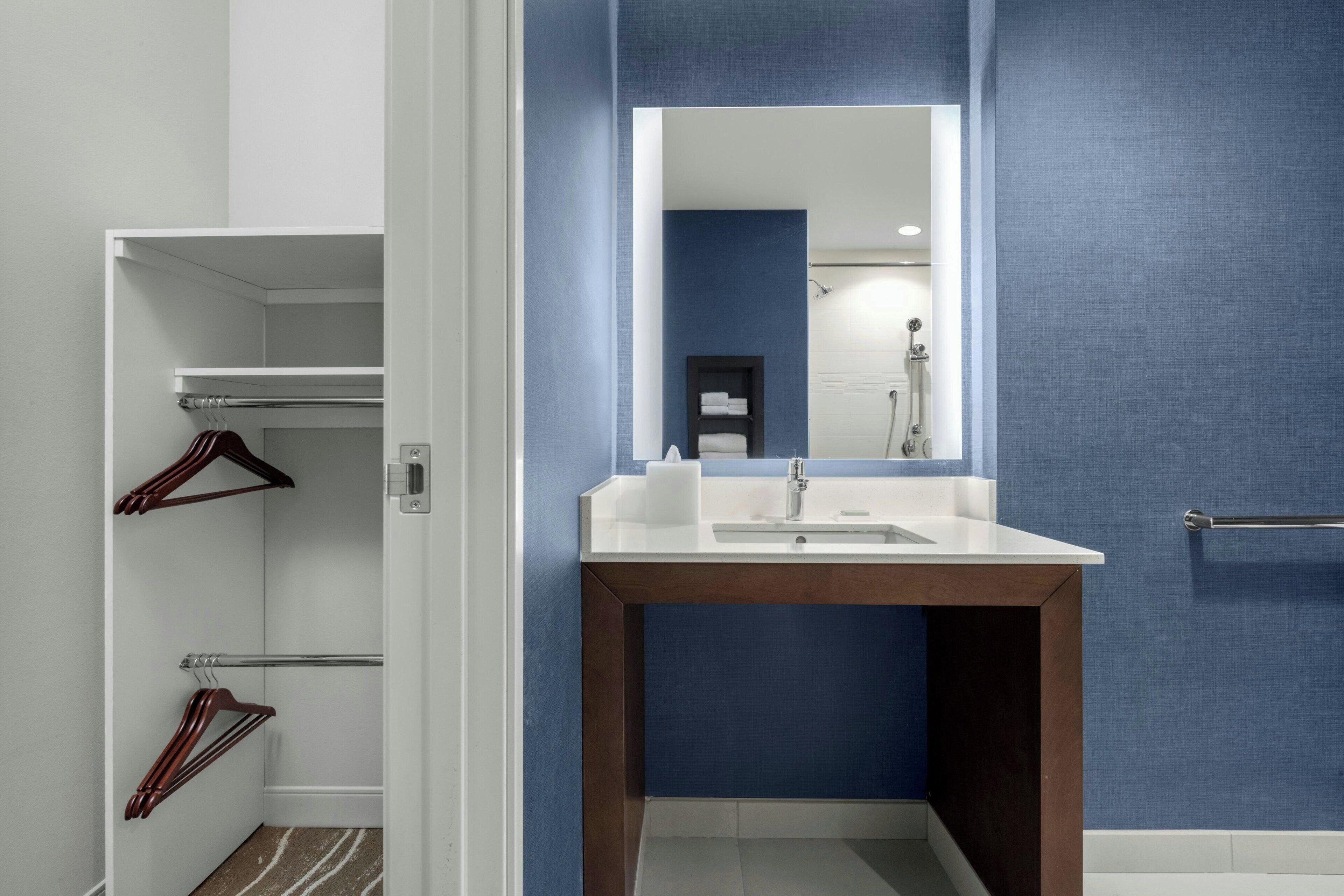 A modern bathroom with a white vanity, a mirror, and a blue wall.
