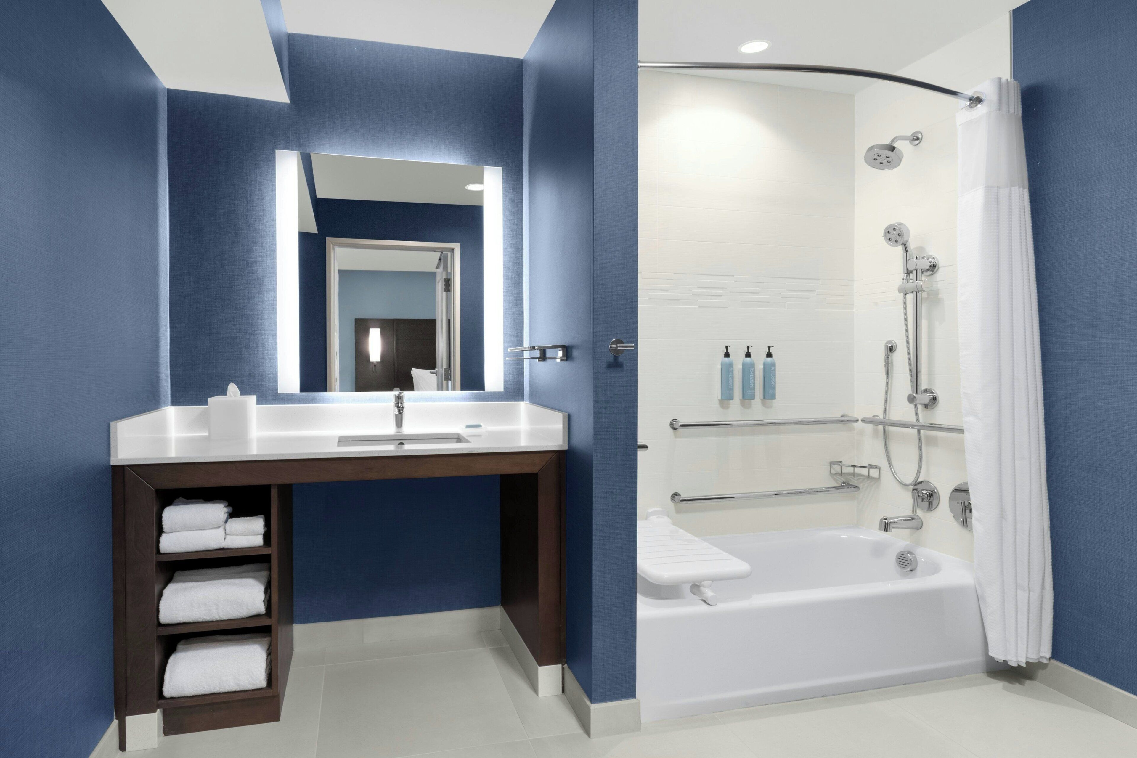 Un baño moderno con un lavamanos blanco, tocador de madera oscura y zona de ducha con mampara de vidrio.