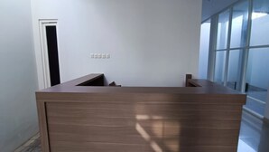 Un mostrador de recepción moderno con un diseño minimalista, una puerta a la izquierda y un amplio ventanal a la derecha.