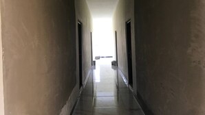 Un pasillo largo y estrecho con piso pulido que conduce a un espacio amplio y luminoso al final.