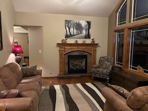 A living room with a fireplace, a sofa set, a patterned rug, and a painting on the wall.