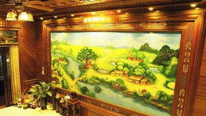 Une grande fresque représentant un paysage rural avec une rivière, des maisons et des arbres.