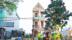 Un bâtiment avec une structure à toit de chaume à l’avant, une enseigne et une table garnie de fruits.