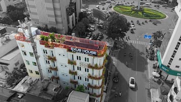 A multi-story building with balconies, a rooftop garden, and a sign reading "NEXUS HOUSE Boutique Hotel".