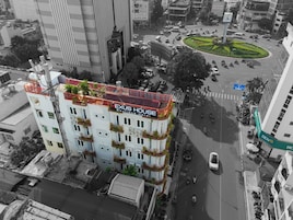 Un edificio de varios pisos con balcones, un jardín en la azotea y un letrero que dice "NEXUS HOUSE Boutique Hotel".