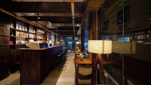 Un'area bar con mobili in legno, un bancone con bottiglie e un'ampia finestra.