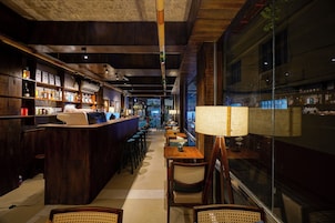 Una zona de bar con muebles de madera, una barra con botellas y un ventanal grande.