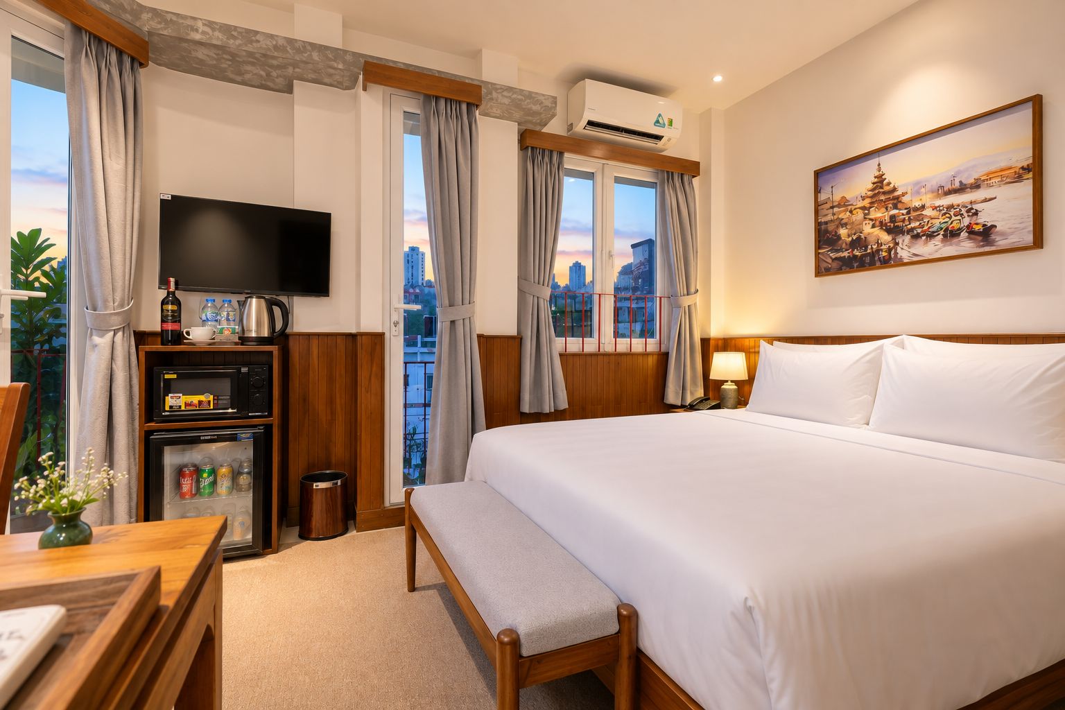 Habitación de hotel con cama, televisión, minibar, ventana con cortinas y un cuadro en la pared.