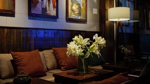 A living room with a sofa, a coffee table with a vase of flowers, and a lamp. - Nexus House Nguyen Binh Khiem - Near Saigon Zoo & Botanical Gardens (Ho Chi Minh City)