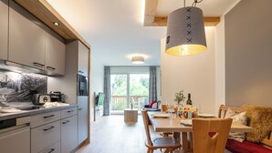 Una cocina moderna con electrodomésticos integrados, un comedor con mobiliario de madera y un ventanal con vistas al exterior.
